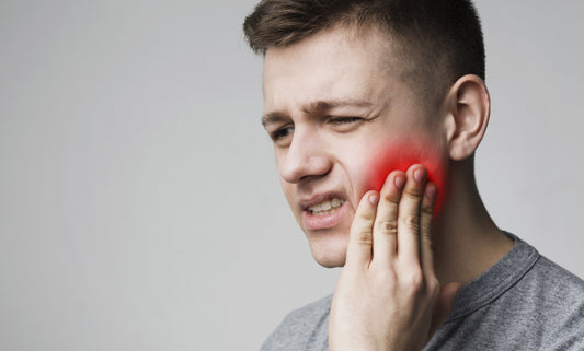 Individual holding jaw in discomfort, indicating common TMJ symptoms like pain and difficulty chewing